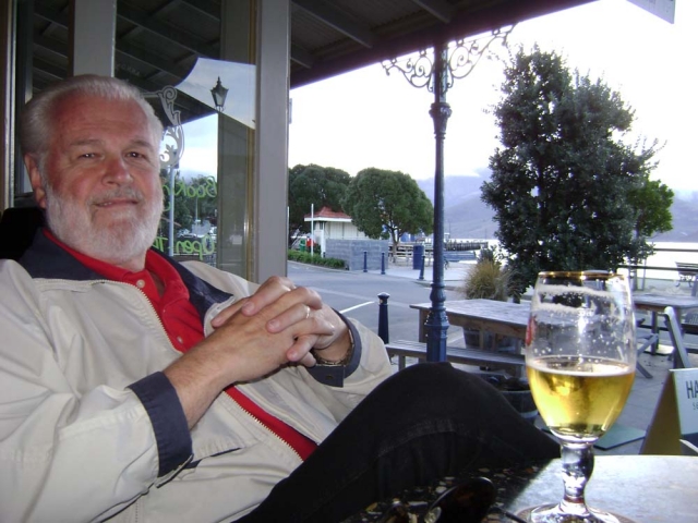 Steve Butcher is relaxing with some NZ wine at Akaroa, their favorite spot in New Zealand. This is gorgeous place a short drive from Christchurch on the south island of New Zealand.  You can cruise the bay for whale and dolphin watching, hang out at the b